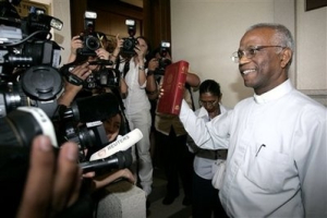 The Herald's editor, Rev. Lawrence Andrew, holding the Holy Bible, poses for photographers outside a courtroom in Kuala Lumpur, Malaysia, Thursday, Dec. 31, 2009. The Malaysian court ruled Thursday that Christians have the constitutional right to use the word Allah while referring to God, striking down an old government ban as illegal. <br/>AP Photo / Lai Seng Sin