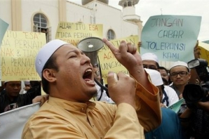 Muslims protest outside a mosque in central Kuala Lumpur, Malaysia, Friday, Jan. 8, 2010. Three Malaysian churches were attacked with firebombs, causing extensive damage to one, as Muslim worshippers pledged Friday to prevent Christians from using the word 'Allah,' escalating religious tensions in this multi-racial country. Many of the country's Malay Muslims, who make up 60 percent of the population, are incensed by a recent High Court decision to overturn a ban on Roman Catholics using 'Allah' as a translation for God in the Malay-language edition of their main newspaper, the Herald. <br/> AP Photo / Mark Baker