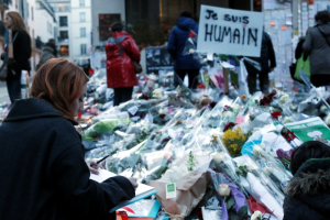 A woman stands among flowers as she signs a book of condolences placed in front of the offices of weekly satirical newspaper Charlie Hebdo in Paris January 14, 2015. <br/> REUTERS/Gonzalo Fuentes