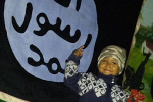 Alleged picture of the toddler posing in front of an ISIS flag in 2014. It was tweeted by Umm Khattab, the teenaged widow of an ISIS fighter with the caption: 'Next generation, Bi'ithnillah (God willing)'  <br/>