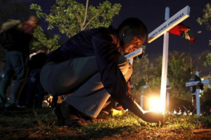 A woman lights a candle on a wooden cross after a memorial concert for the Garissa university students who were killed during an attack by gunmen, at the ''Freedom Corner'' in Kenya's capital Nairobi April 14, 2015. REUTERS/THOMAS MUKOYA <br/>
