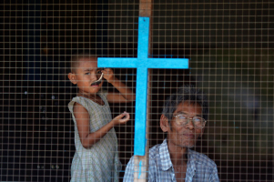 A man and a child from a Christian family look out from their home in the industrial suburbs of Yangon on April 14, 2012. Photo courtesy of REUTERS/Damir Sagolj  <br/>