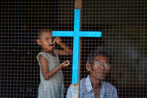 A man and a child from a Christian family look out from their home in the industrial suburbs of Yangon on April 14, 2012. Photo courtesy of REUTERS/Damir Sagolj  <br/>