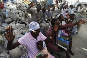 People pray outside a destroyed church in Port-au-Prince, Sunday, Jan. 24, 2010. Haiti's government has declared an end to searches for living people trapped under debris, and officials are shifting their focus to caring for the thousands of survivors living in squalid, makeshift camps. <br/>AP Images / Rodrigo Abd