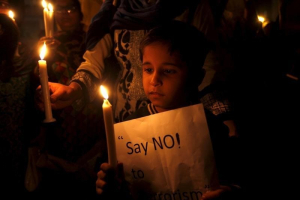 A child holds a candle and sign against terrorism at a vigil in Karachi, Pakistan, December 16, 2015.  <br/>REUTERS/Akhtar Soomro