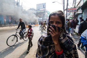 A woman covers her face as protesters light fuel in a city center. <br/>Al Jazeera