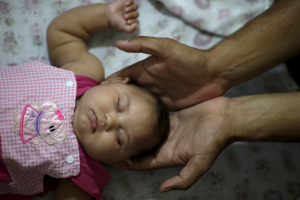 Felipe holds the head of his daughter Maria Geovana, who has microcephaly, at his house in Recife, Brazil, January 25, 2016.  <br/>REUTERS/Ueslei Marcelino