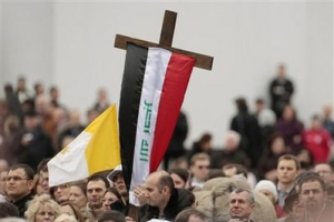 A man holds a cross wrapped by the Iraqi flag during Pope Benedict XVI's Angelus prayer in St. Peter's square, at the Vatican, Sunday, Feb. 28, 2010. The Pontiff appealed to the Iraqi authorities to provide security to the Christian minority in Iraq, following the recent spate of killings against Christians. <br/>AP Images / Gregorio Borgia