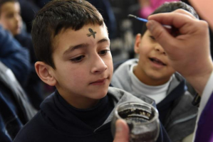 A Catholic priest places ashes on the forehead of a boy during mass on Ash Wednesday in the Latin Patriarchate Catholic School in Beit Jala, West Bank, February 10, 2016 <br/>