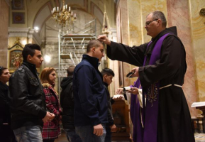 A Catholic priest places ashes on the head of a boy during mass on Ash Wednesday in the St. Savior's Church in the Old City of Jerusalem, February 10, 2016. <br/>