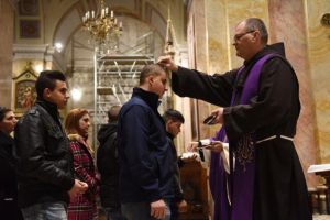 A Catholic priest places ashes on the head of a boy during mass on Ash Wednesday in the St. Savior's Church in the Old City of Jerusalem, February 10, 2016. <br/>