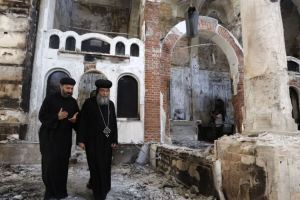Bishop-General Macarius, a Coptic Orthodox leader, walks around a burnt and damaged church in Minya, about 245 km (152 miles) south of Cairo, in August 2013. Egypt's Coptic Christians, who make up 10 percent of its 85 million people, have coexisted with the majority Sunni Muslims for centuries. Reuters <br/>