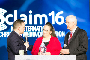 Jerry Johnson, president and chief executive officer of the National Religious Broadcasters (on left), presents the NBR President's Award to Kentucky county clerk Kim Davis at the Proclaim 16 Convention Wednesday in Nashville, Tenn. Liberty Counsel chairman and founder Mat Staver stood with Davis at the podium; he served as her attorney during recent legal matters after she refused to sign marriage licenses for same-sex marriages.  <br/>The Gospel Herald