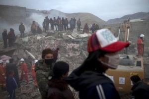 People gather on the debris of a collapsed building while rescuers work on the site in the earthquake-hit Jiegu town, Yushu, in west China's Qinghai province, Thursday, April 15, 2010. Rescue teams fought gusty winds and altitude sickness Thursday as survivors faced a second night outside in freezing weather after strong earthquakes left hundreds of people dead and thousands hurt in a mountainous Tibetan area of western China. <br/>AP Photo / Alexander F. Yuan