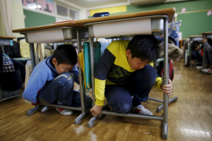 School children take shelter under desks during an earthquake simulation exercise in an annual evacuation drill at an elementary school in Tokyo March 11, 2016, to mark the five-year anniversary of the March 11, 2011 earthquake and tsunami that killed thousands and set off a nuclear crisis. <br/>