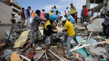 Volunteers remove a body from a destroyed house in Pedernales, Ecuador, on April 17. (Dolores Ochoa/AP) <br/>