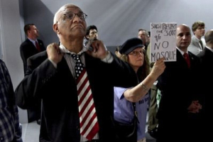 Arish Sahani, left, of New York, puts on an American Flag tie, and Linda Rivera, right, of New York, stand in opposition as groups planning a proposed mosque and cultural center near Ground Zero in Lower Manhattan to be named Cordoba House showed and spoke about their plans for the center at a community board meeting in New York Tuesday, May 25, 2010. Community members both for and against the plan spoke during the meeting. <br/>AP Images / Craig Ruttle