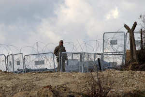 A Turkish soldier standing guard is seen from the Syrian town of Khirbet Al-Joz at the Turkish-Syrian border, in Latakia countryside, where internally displaced Syrian people are waiting to get permission to cross into Turkey, February 7, 2016. REUTERS/Ammar Abdullah <br/>