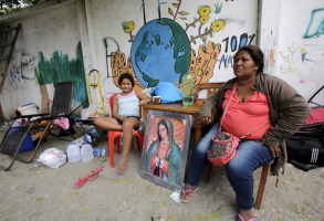 A woman and her daughter rest next to an image of the Virgin of Guadalupe outside their home in Pedernales, after an earthquake struck off the Pacific coast, April 20, 2016. REUTERS/Henry Romero <br/>