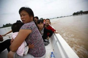 Local flood victims sit in a rescue boat as they head towards a temporary shelter after being evacuated from flooded homes in the outskirts of Yingtan,Jiangxi province June 21, 2010. Heavy rain across a swathe of southern China over the last week has killed at least 175 people and left 107 missing, as rivers broke their banks and landslides cut off road and rail links, state media said on Monday. <br/>REUTERS/Aly Song