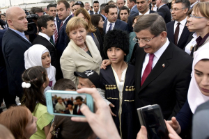 Turkish Prime Minister Davutoglu and German Chancellor Merkel pose for pictures with the refugees. More refugees and immigrants are interested to convert to Christians. <br/>Photo: Reuters