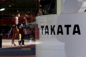 A logo of Takata Corp is seen with its display as people are reflected in a window at a showroom for vehicles in Tokyo, November 6, 2015.  <br/>REUTERS/Toru Hanai/File Photo