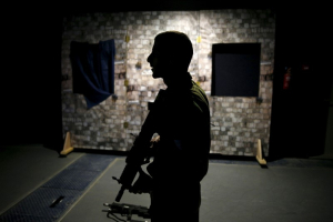 An Israeli soldier is silhouetted as he takes part in an open-fire scenario training in which soldiers respond with laser-firing rifles to a simulated Palestinian attack playing out on an interactive screen, at Camp Tsur infantry training base in southern Israel, near Yeruham March 24, 2016.  <br/>REUTERS/Amir Cohen