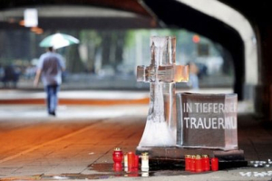 A cross and a cube made of ice stand near the entrance tunnel of the Love Parade in Duisburg, Germany, on Monday, July 26, 2010. Letters on the cube read 'In Deep Mourning'. <br/>AP Images / Clemens Bilan
