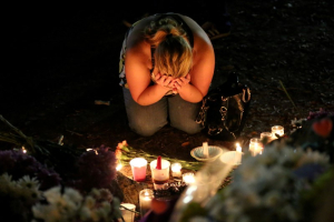 A woman mourns as she sits on the ground and takes part in a vigil for the Pulse night club victims following last week's shooting in Orlando, Florida. <br/> REUTERS/Carlo Allegri