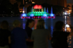 People take part in a vigil for the Pulse night club victims as the Lake Enola fountain is lit in rainbow colors following last week's shooting in Orlando, Florida, U.S., June 19, 2016.  <br/>REUTERS/Carlo Allegri
