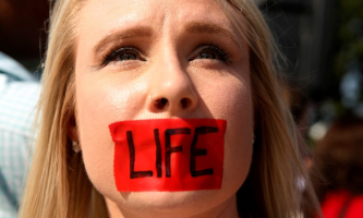 An anti-abortion protester with tape over her mouth demonstrates outside the U.S. Supreme Court before the court handed a victory to abortion rights advocates, striking down a Texas law imposing strict regulations on abortion doctors and facilities in Washington June 27, 2016.  <br/>REUTERS/Kevin Lamarque