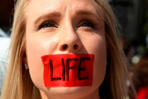 An anti-abortion protester with tape over her mouth demonstrates outside the U.S. Supreme Court before the court handed a victory to abortion rights advocates, striking down a Texas law imposing strict regulations on abortion doctors and facilities in Washington June 27, 2016.  <br/>REUTERS/Kevin Lamarque