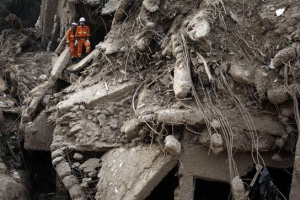 Two rescue workers stand among the remains of a collapsed building after a mudslide swept through the town of Zhouqu on Aug. 10. <br/>(Ng Han Guan / AP)