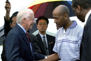 In this photo released by Korean Central News Agency via Korea News Service in Tokyo, former U.S. President Jimmy Carter, left, and Aijalon Gomes, second right, react as they prepare to leave North Korea from Pyongyang airport, Friday, Aug. 27, 2010. Looking gaunt but relieved, Gomes freed after nearly seven months jailed in North Korea left Pyongyang on Friday in the company of former U.S. President Jimmy Carter. <br/>AP Images / Korean Central News Agency via Korea News Service