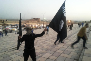 A fighter of the Islamic State of Iraq and the Levant (ISIL) holds an ISIL flag and a weapon on a street in the city of Mosul, June 23, 2014. <br/> REUTERS/Stringer