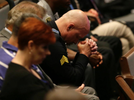 A police officer bows his head during the funeral for Dallas Police. <br/>AP Photo