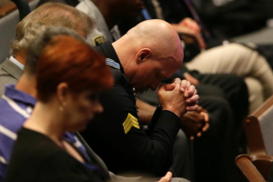 A police officer bows his head during the funeral for Dallas Police. <br/>AP Photo