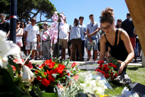 A woman places a bouquet of flowers as people pay tribute near the scene where a truck ran into a crowd at high speed killing scores and injuring more who were celebrating the Bastille Day national holiday, in Nice, France, July 15, 2016.  <br/>REUTERS/Pascal Rossignol