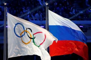 The Russian national flag (R) and the Olympic flag are seen during the closing ceremony for the 2014 Sochi Winter Olympics, Russia, February 23, 2014.  <br/>REUTERS/Jim Young/File Photo