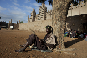 A man practices reciting Quranic verses handwritten on a piece of wood in front of the Grand Mosque of Djenne, Mali September 1, 2012.  <br/>REUTERS/Joe Penney