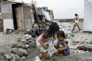 In this Sept. 2, 2010 photo, two girls play beside an open sewer in the sprawling slum on the edge of the Philippines' Manila Bay. As the U.N. holds a September 2010 summit to review progress in helping the world's have-nots, the good news is a sharp decline in Asian poverty rates, thanks largely to robust economic growth in China and India. <br/>AP Images / Pat Roque