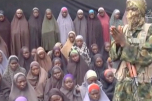 A still image from a video posted by Nigerian Islamist militant group Boko Haram on social media, seen by Reuters on August 14, 2016, shows a masked man talking to dozens of girls the group said are school girls kidnapped in the town of Chibok in 2014.  <br/>Social Media