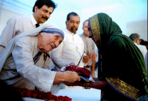 Mother Teresa presents documents for a new house to a villager from Latur in Bombay September 26, 1994.  <br/>REUTERS/Savita Kirloskar/File Photo