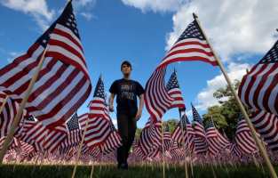 Jackson Tucker walks through the field  of 3,000 U.S. flags placed in memory of the lives lost in the September 11, 2001 attacks, at a park in Winnetka, Illinois, September 10, 2016. REUTERS/Jim Young <br/>