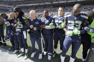 Seattle Seahawks players and coaches stand and link arms during the singing of the national anthem before an NFL football game against the Miami Dolphins, Sunday, Sept. 11, 2016, in Seattle. <br/>AP Photo/Elaine Thompson