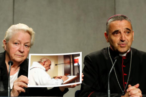 Roselyne Hamel (left), sister of Father Jacques Hamel holds a picture next to Archbishop of Rouen Dominique Lebrun during a media conference at the Vatican, Sept. 14, 2016.  The French priest was knifed to death at his altar by Islamist militants in July. Pope Francis just declared Hamel was a martyr, and indicated the priest already was on the road to sainthood. <br/>REUTERS / Stefano Rellandini