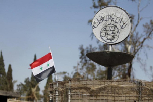 A Syrian national flag flutters next to the Islamic State's slogan at a roundabout where executions were carried out by ISIS militants in the city of Palmyra, in Homs Governorate, Syria in this April 1, 2016 file photo.  <br/>Reuters/Omar Sanadiki/Files 
