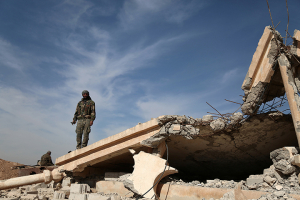 An Syrian Democratic Forces (SDF) fighter stands with his weapon on the rubble of a destroyed building, north of Raqqa city, Syria. REUTERS/Rodi Said <br/>