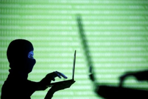 People wearing balaclavas are silhouetted as they pose with a laptops in front of a screen projected with the word 'cyber.' March 29, 2016 11:03pm EDT<br />
<br />
 <br/>Reuters/Dado Ruvic 