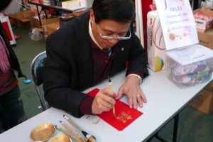 Rev. Sam H. C. Luk, general secretary of the Hong Kong Chinese Christian Churches Union, muster couplets with his best calligraphic style on vertical strips of red paper while his ministry’s co-workers passed them out to by-passers. <br/>Gospel Herald 